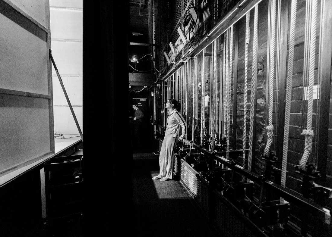 Schwarz-Weiß-Foto einer Schauspielerin hinter der Bühne während der Produktion von "Der Wind in den Weiden" am Theater Lüneburg.