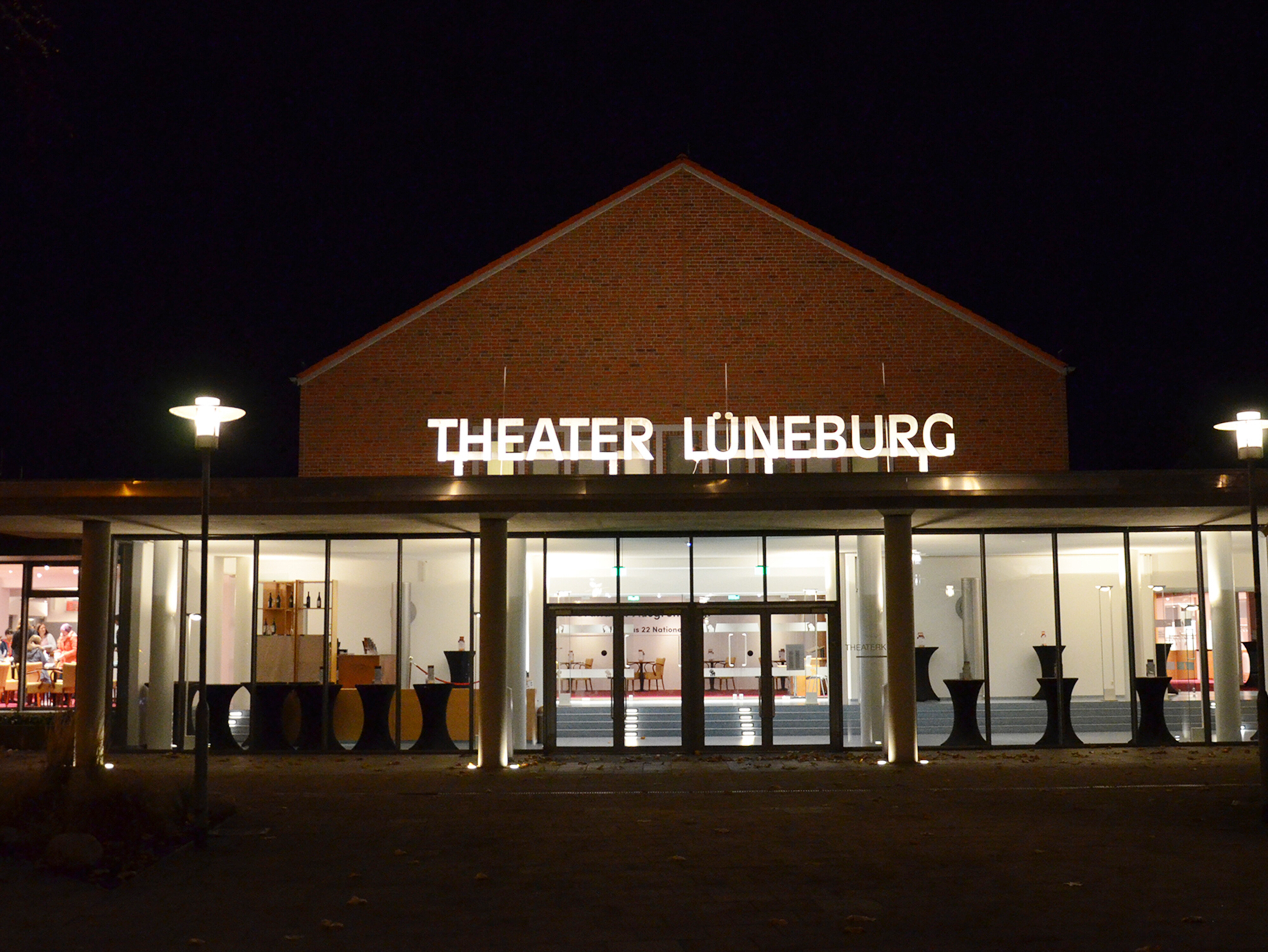 Theater Lüneburg bei Nacht, Außenansicht des Gebäudes mit beleuchtetem Eingang. Foto: Kozycki.
