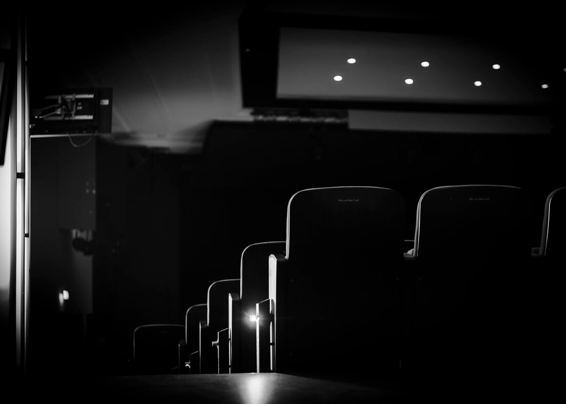 Leere Theaterstühle in einem dunklen Zuschauerraum, beleuchtet durch dezente Lichter während des Kammerkonzerts Nr. 4 im Theater Lüneburg.